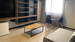 A modern living room with a flat-screen TV, built-in shelves, a coffee table, two chairs, and a sofa. - Solar Pedra da Ilha (Penha)