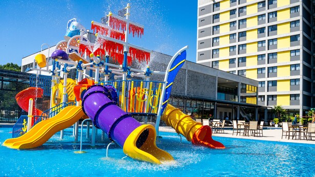 A water park with slides and water features, a pool, and a building with balconies and windows. - Solar Pedra da Ilha (Penha)