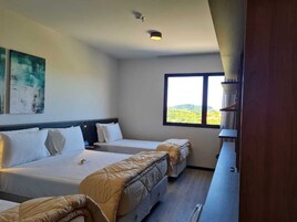 Una habitación de hotel con dos camas, un ventanal con vistas al exterior y una lámpara en el techo.
