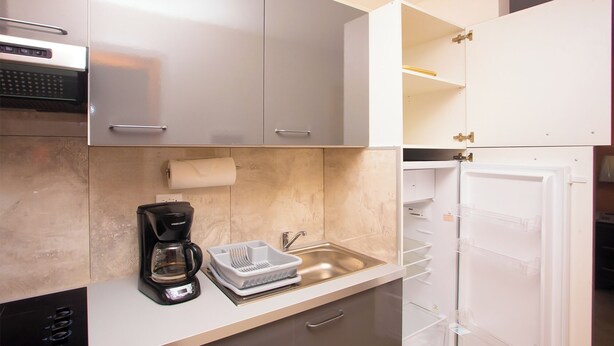 Una cocina moderna con cafetera, pileta y refrigerador.