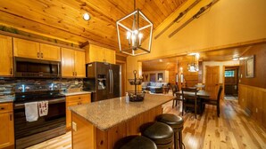 A kitchen with wooden cabinets, a granite countertop, a stainless steel refrigerator, and a hanging light fixture. - Spacious Lakefront Lodge, Kayaks/Canoes Included! Pet Friendly! (Tomahawk)