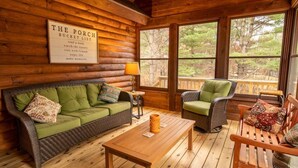 A cozy porch area with a wicker sofa, a wooden table, and a wicker chair. A sign titled "The Porch Bucket List" is visible on the wall. - Spacious Lakefront Lodge, Kayaks/Canoes Included! Pet Friendly! (Tomahawk)