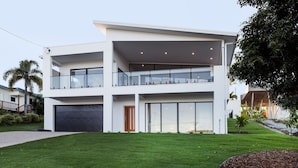 A modern two-story house with a flat roof, large windows, and a visible garage. - Airlie Bay View (Airlie Beach)