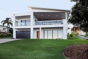 A modern two-story house with a flat roof, large windows, and a visible garage. - Airlie Bay View (Airlie Beach)