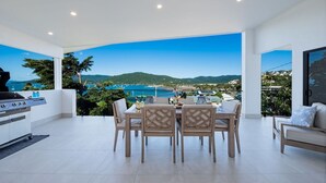 A dining area with a view of the sea and hills. - Airlie Bay View (Airlie Beach)