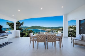 A dining area with a view of the sea and hills. - Airlie Bay View (Airlie Beach)