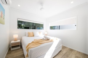 Ein modernes Schlafzimmer mit einem großen Bett, Nachttischen und einem Fenster.