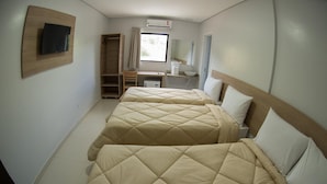 Habitación de hotel con dos camas, un escritorio, un armario, un televisor y una ventana.
