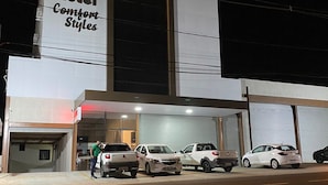 Un hotel con un letrero que dice "Hotel Comfort Styles" y un estacionamiento con varios coches.
