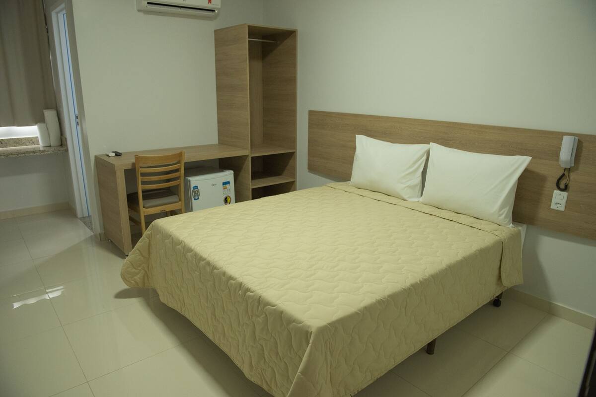 A bedroom with a bed, a desk, and a wardrobe.