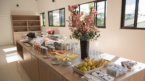 Un bufé con diversas frutas, un jarrón de flores y diferentes recipientes de comida.
