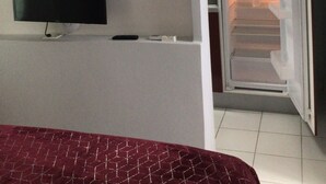Una cucina compatta con TV integrata, frigorifero e forno a microonde.