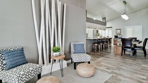 Un soggiorno moderno con un divano, poltrone, un tavolino da caffè e un elemento decorativo a parete.