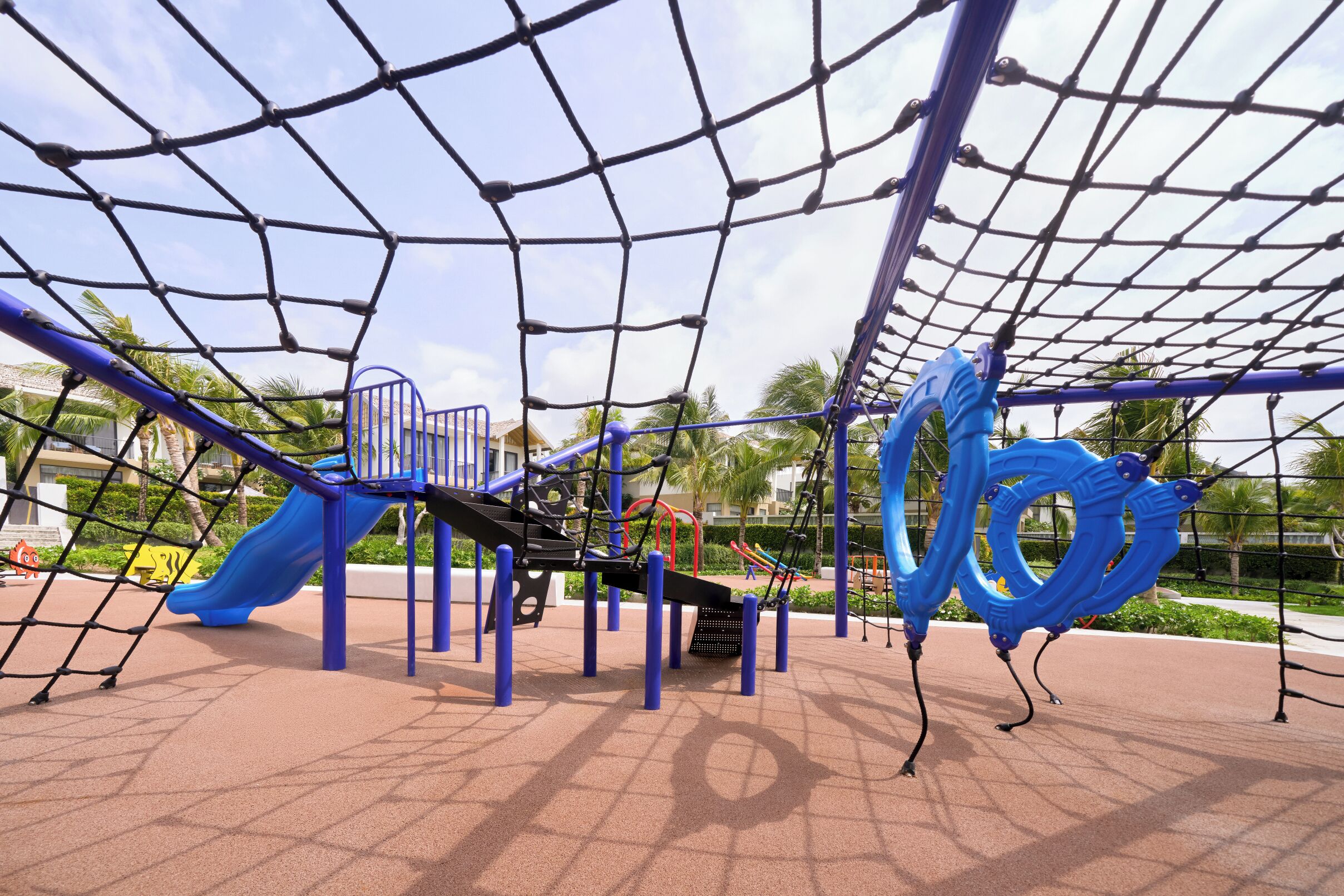 A playground with a netted climbing area, slides, and a blue spiral structure.