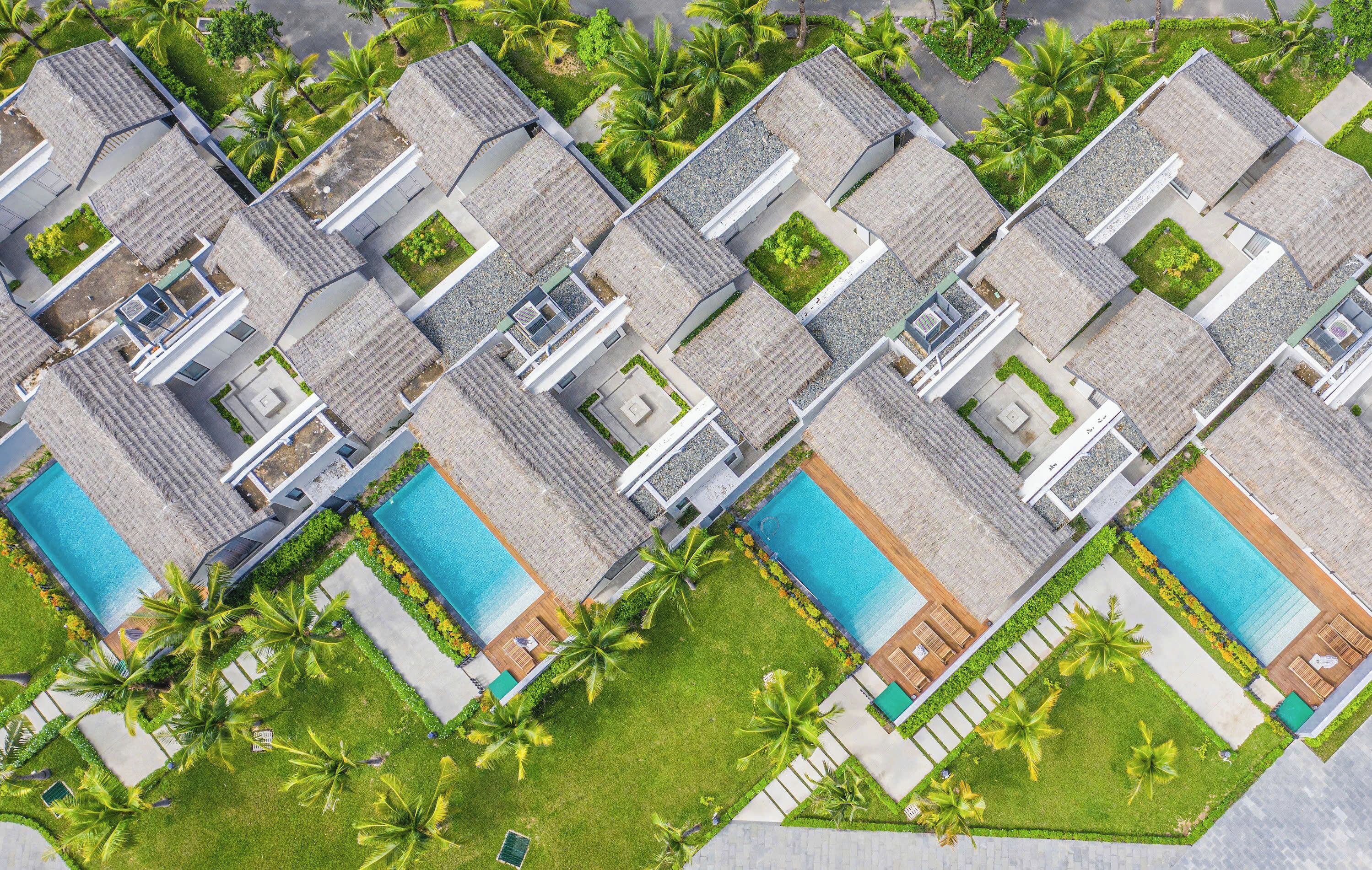 Ein modernes Resort mit mehreren Schwimmbecken, üppigen Rasenflächen und Palmen.