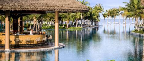A pool area with a bar, lounge chairs, and umbrellas.