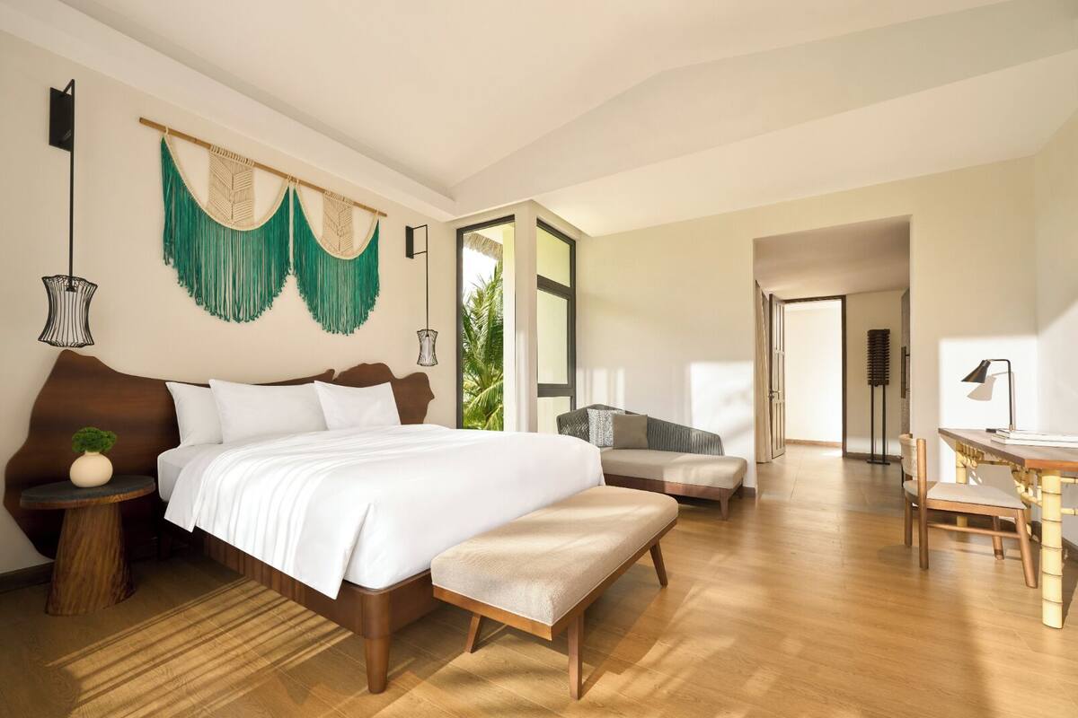 A modern bedroom with a large bed, a seating area, and a dining table.