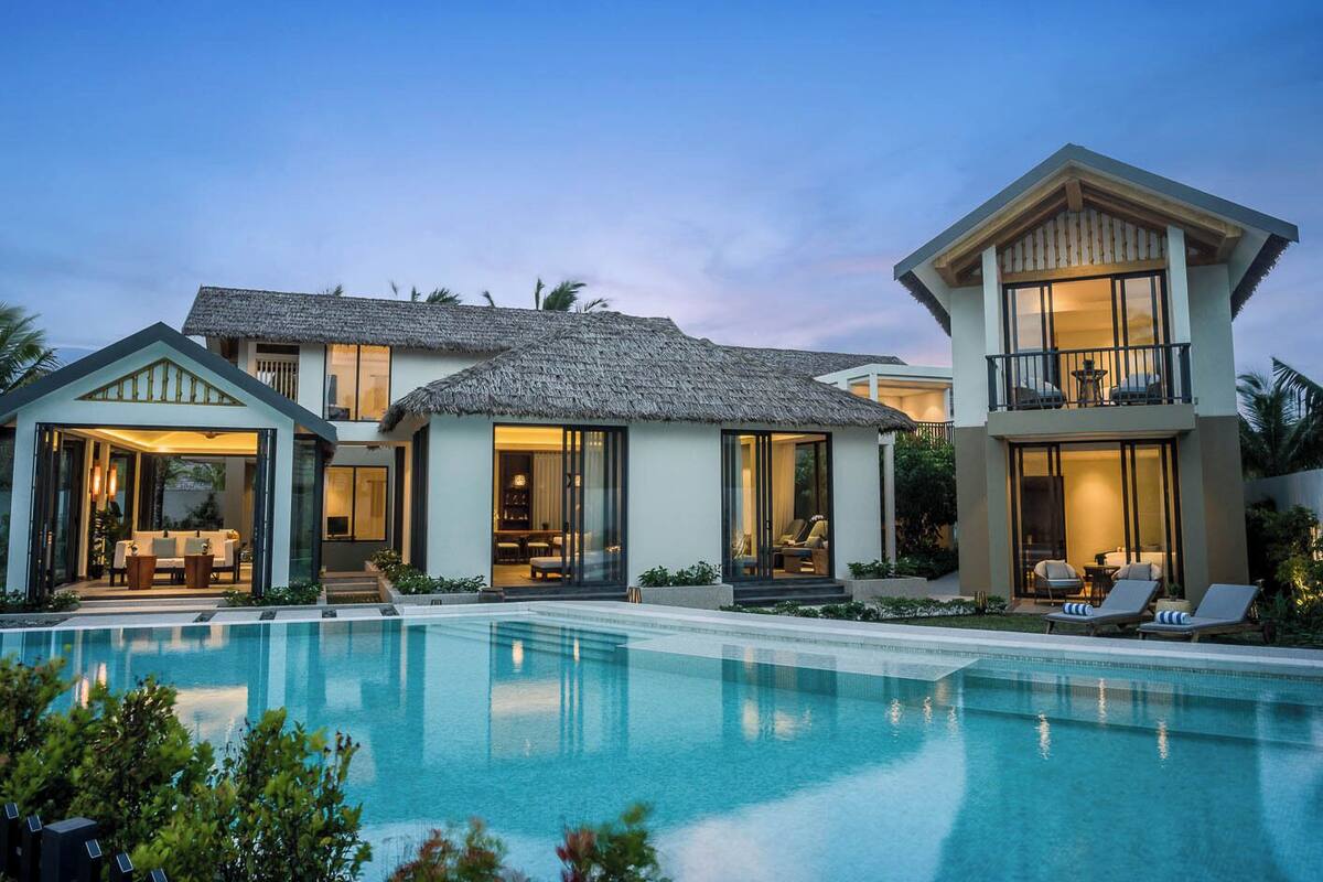 A modern two-story house with a swimming pool, large windows, and a balcony.