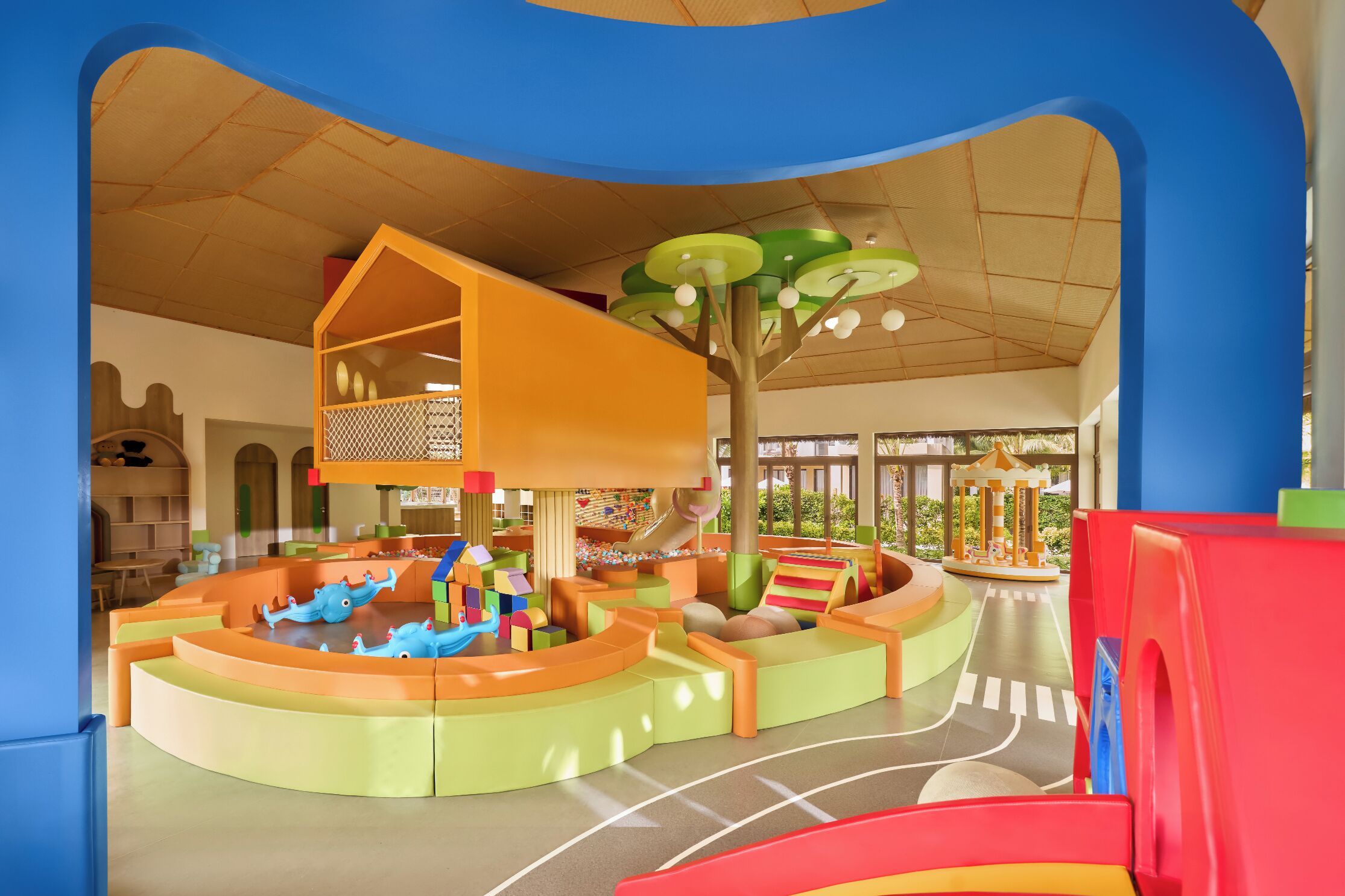 Un área de juegos infantiles con un tobogán, estructuras para escalar y un carrusel.