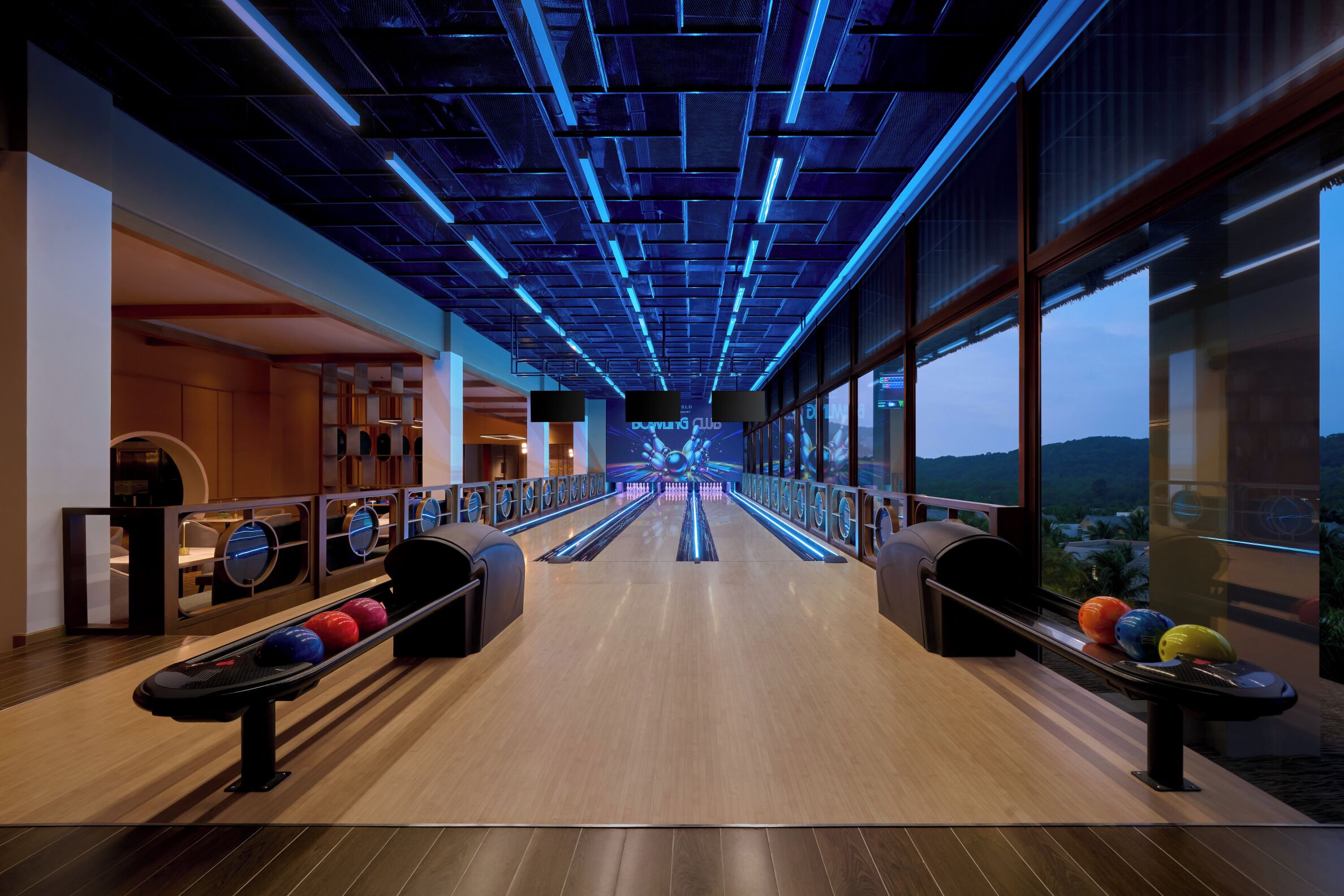 Eine Bowlinghalle mit modernem Design, ausgestattet mit einer langen Gasse mit Bowlingbahnen und einer Decke mit blauer Beleuchtung.