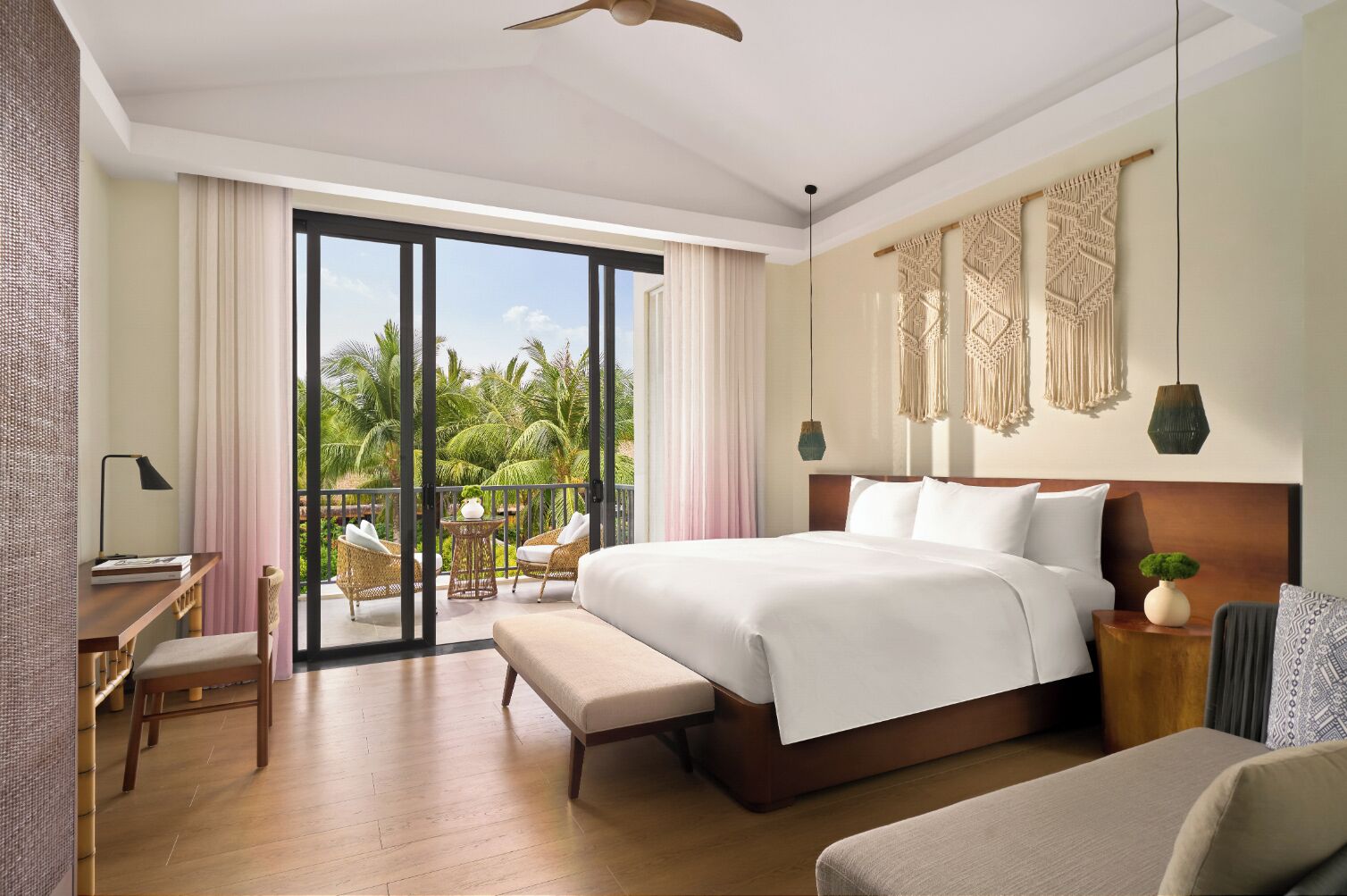 A spacious bedroom with a large bed, a desk, and a balcony with outdoor seating.