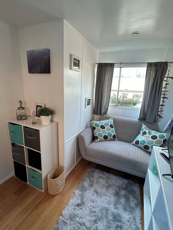 A modern living room with a grey sofa, teal storage unit, and a fluffy grey rug.