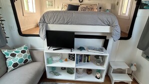 En kompakt opholdsstue med køjeseng, sofa, lille bord og reol.