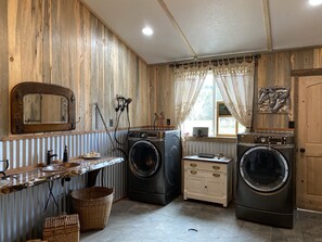 A laundry room with wooden walls, two washing machines, a sink, and a mirror. - Beautifully decorated Cottage on 30 acre ranch, accommodations for horses extra  (Springfield)