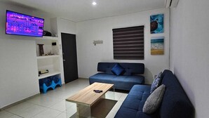 A modern living room with a blue sofa, a coffee table, and a TV mounted on the wall.