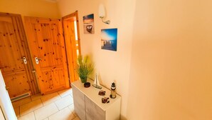 Eine Holztür mit Schlüsselloch, ein kleiner Blumentopf und eine Wandleuchte.