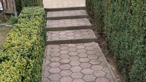 Ein befestigter Weg führt zu einer Terrasse mit Tisch und Stühlen.