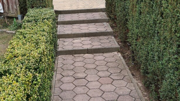 Un sendero pavimentado que conduce a un patio con mesa y sillas.