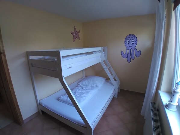 A bunk bed with white bedding in a room with beige walls.