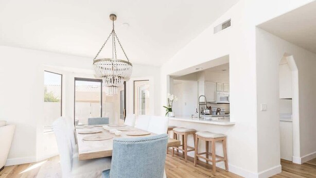 A modern kitchen with white cabinets, a central island, and a hanging chandelier. - Western Hills-Pool Heat Avail- Putting Green-Games (Fountain Hills)