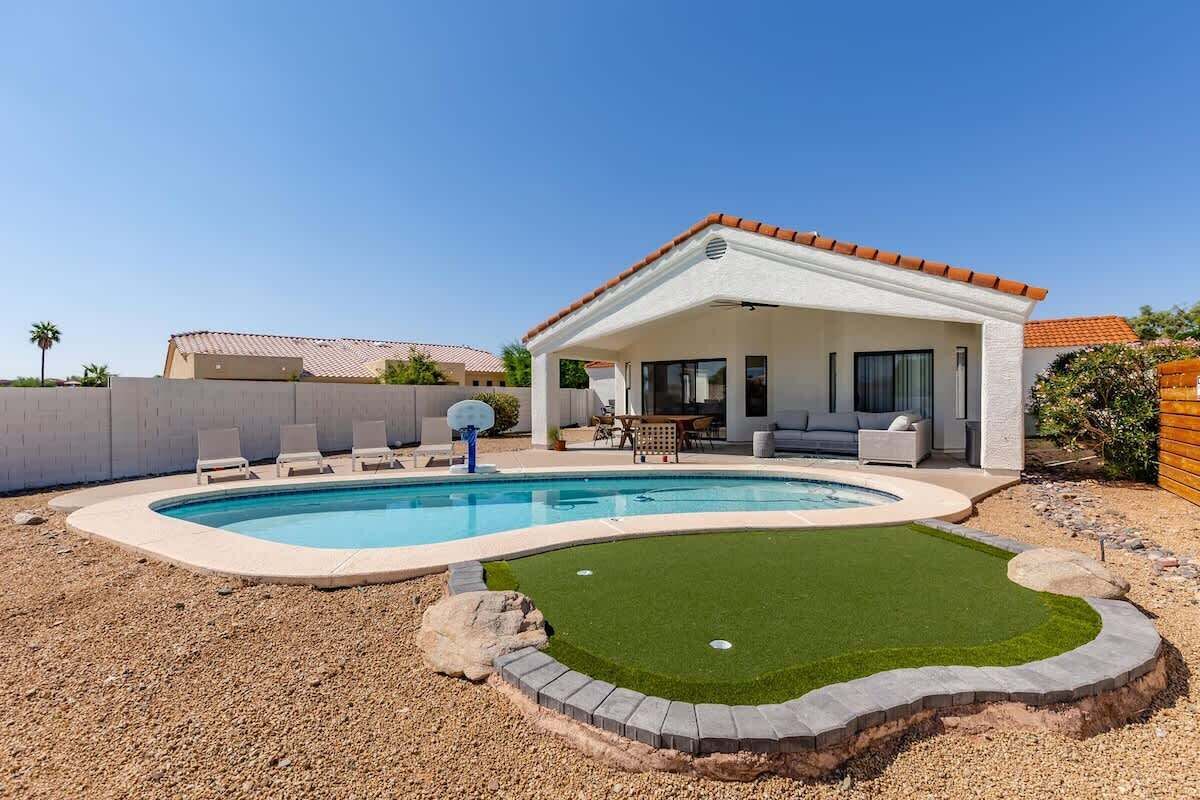 Sparkling heated pool, putting green, fire pit, sun loungers, BBQ, cornhole, and outdoor patio furniture, plus dining area.