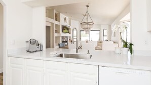A modern kitchen with a white countertop, stainless steel sink, and a built-in dishwasher. - Western Hills-Pool Heat Avail- Putting Green-Games (Fountain Hills)
