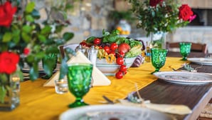 A dining table set with plates, glasses, and a centerpiece of fresh vegetables and flowers. - Villa Dei Golfi , Panorama, Privacy and Quiet (Campania)