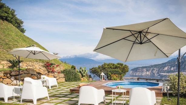 A poolside area with white chairs and umbrellas, a stone wall, and a view of mountains and the sea. - Villa Dei Golfi , Panorama, Privacy and Quiet (Campania)
