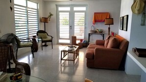Un salon comprenant un canapé, des fauteuils, une table basse et un ventilateur.