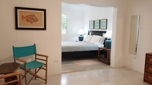 Une chambre avec un lit, deux lampes de chevet, un tableau représentant un poisson encadré, une chaise et un miroir.