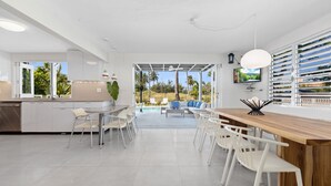 A modern kitchen with a central island, white chairs, and a dining table. - Your own beach house, private pool & pickle ball court, steps to beach.  (Sabana, Vega Alta, Puerto Rico)