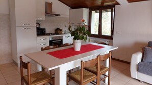 Eine moderne Küche mit weißen Schränken, einer roten Tischdecke und einem Blumentopf.