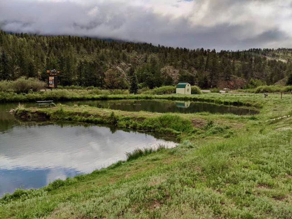 A tranquil lakeside setting with a small cabin and a signboard in the background.