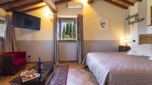 A hotel room with a bed, a red armchair, a TV, a window with curtains, a bedside table with a lamp, and a wall with a 'always together' sign. - La Smarrita by Interhome (Lucignano)