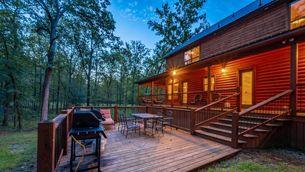 Eine Holzhütte mit einer Terrasse, Sitzgelegenheiten im Freien und einem Grill.