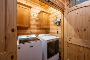 A compact laundry room with wooden walls and two white washing machines. - Coyote Creek: 3 bedroom, 3.5 bath sleeps 11 (Broken Bow)