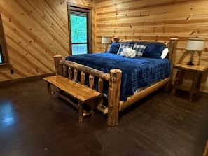 A wooden cabin bedroom with a bed, bench, two bedside tables, and a window. - Coyote Creek: 3 bedroom, 3.5 bath sleeps 11 (Broken Bow)