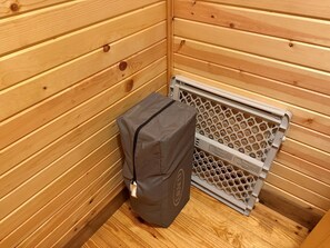 A wooden cabin interior with a small gray bag and a metal vent.