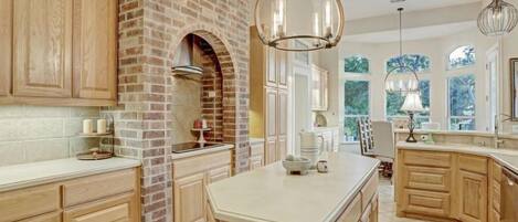 A spacious kitchen with wooden cabinets, a brick accent wall, and a large island.