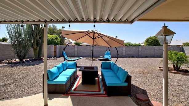 An outdoor patio with a covered seating area, a swing chair, and a cactus plant.